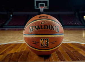 Grupaj strâns al unei mingi de baschet u uzată pe un teren de lemn lustruit